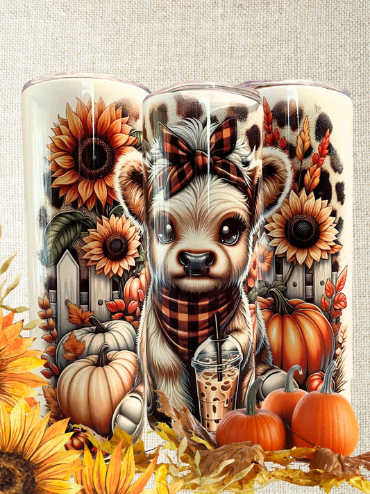 20 oz stainless steel insulated tumbler with cute highland cow wearing an orange and black plaid headband and bandana. Cow is holding an iced coffee, surrounded by pumpkins, fall foliage, and sunflowers, on a cheetah background.