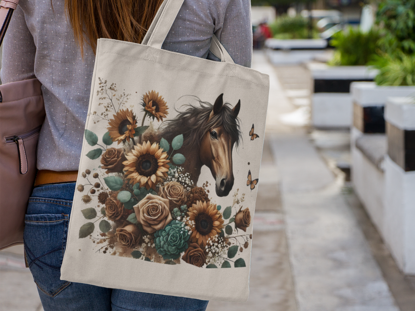 Woman carrying a canvas tote bag with boho style chocolate brown horse, surrounded by sunflowers, roses, and other flowers in blue, brown, and yellow hues.