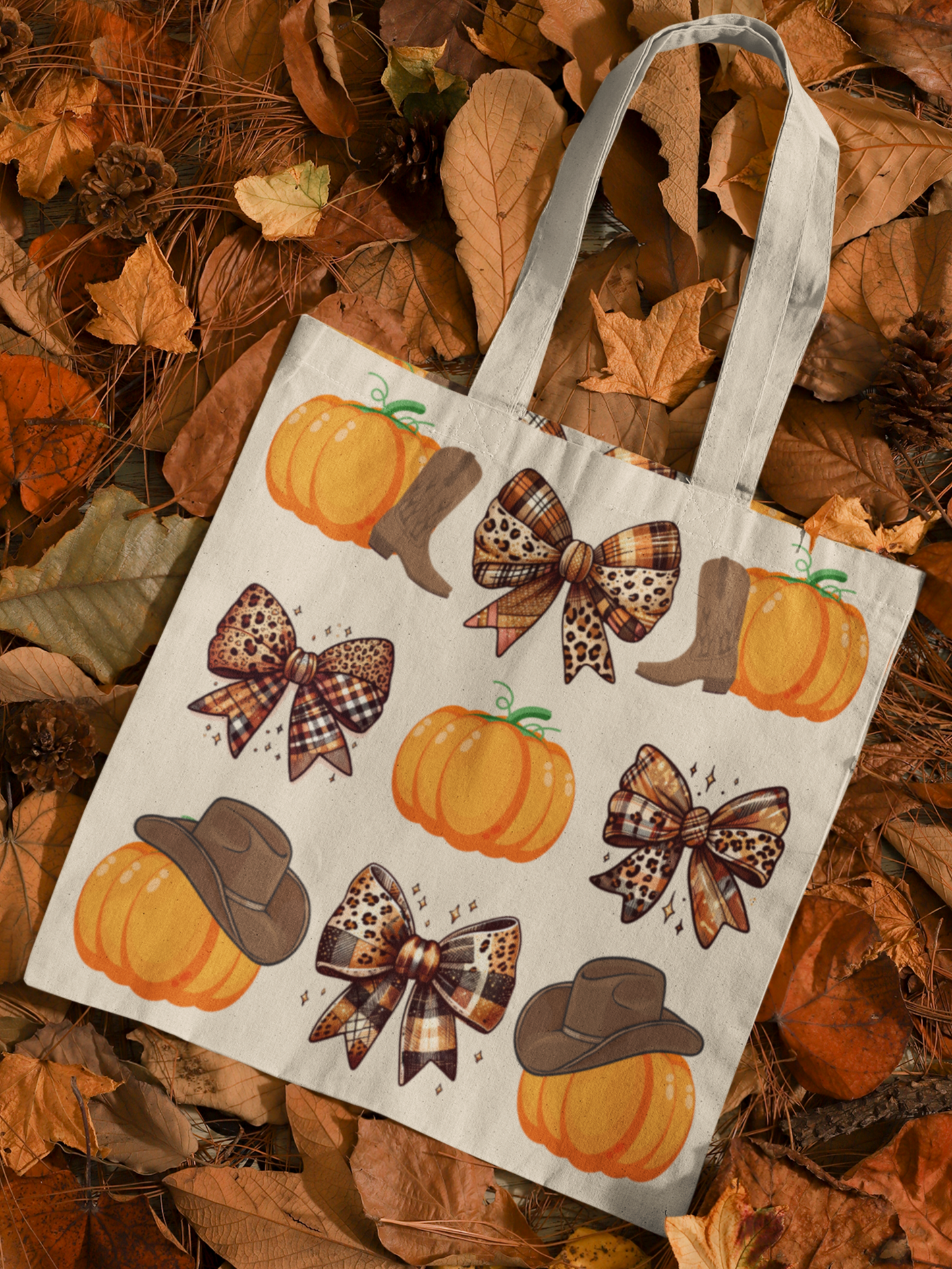 Canvas tote bag with trendy grid print of alternating plaid coquette bows and pumpkins adorned with cowboy boots or cowgirl hats. Tote is laying on a bed of autumn leaves.